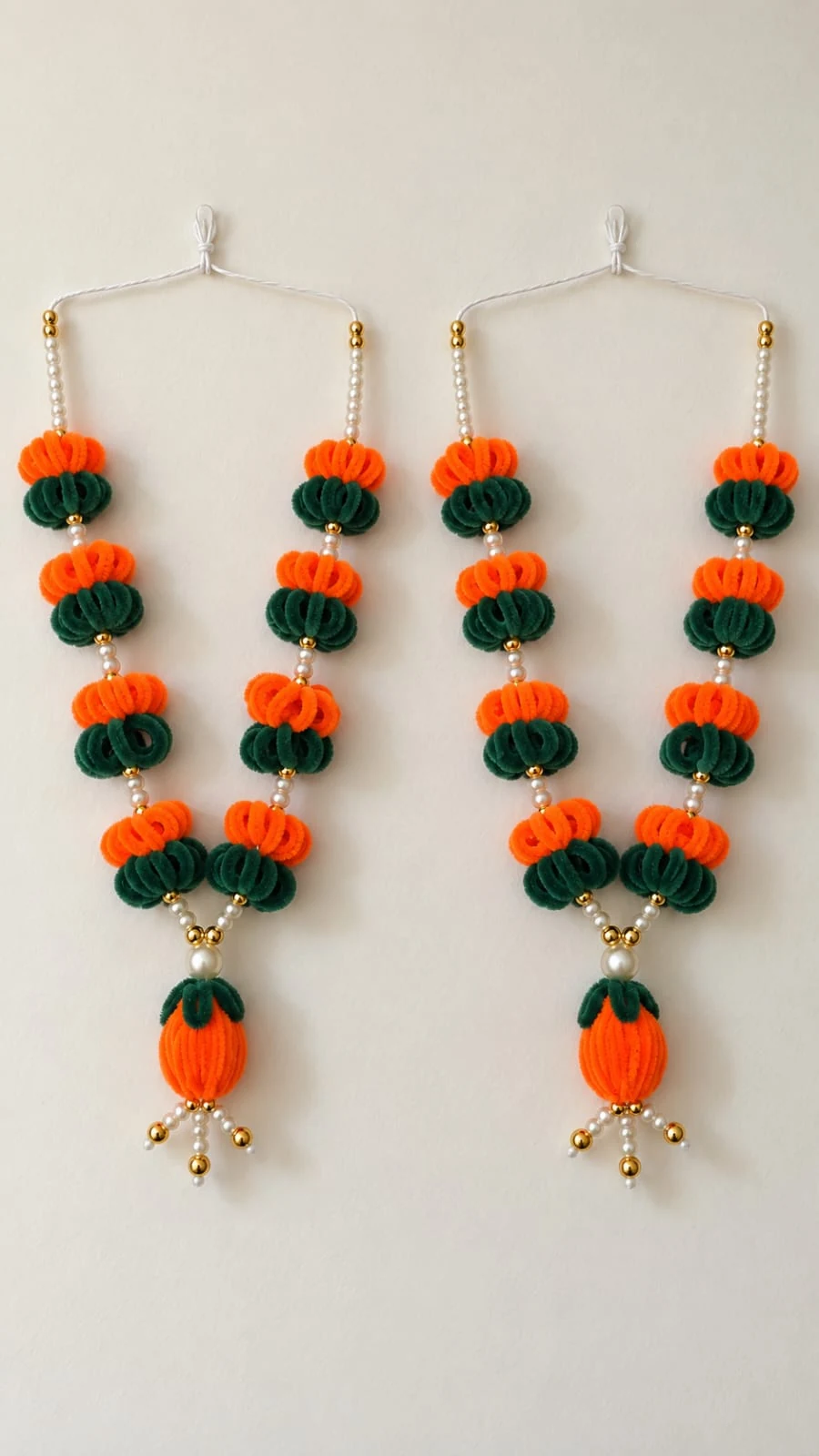 Saffron & Forest Garlands: Bright orange and deep-green floral garlands with pearl-like beads and dangling buds. A pair is pictured.